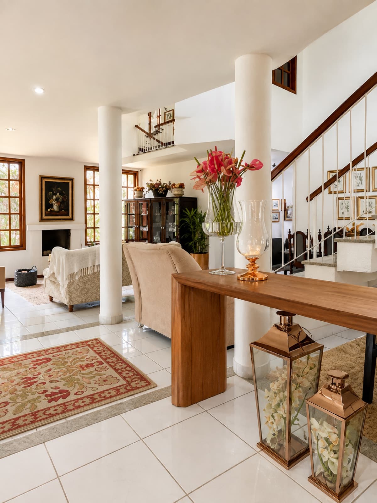 Hall de entrada da pousada com colunas, aparador e arranjo de flores