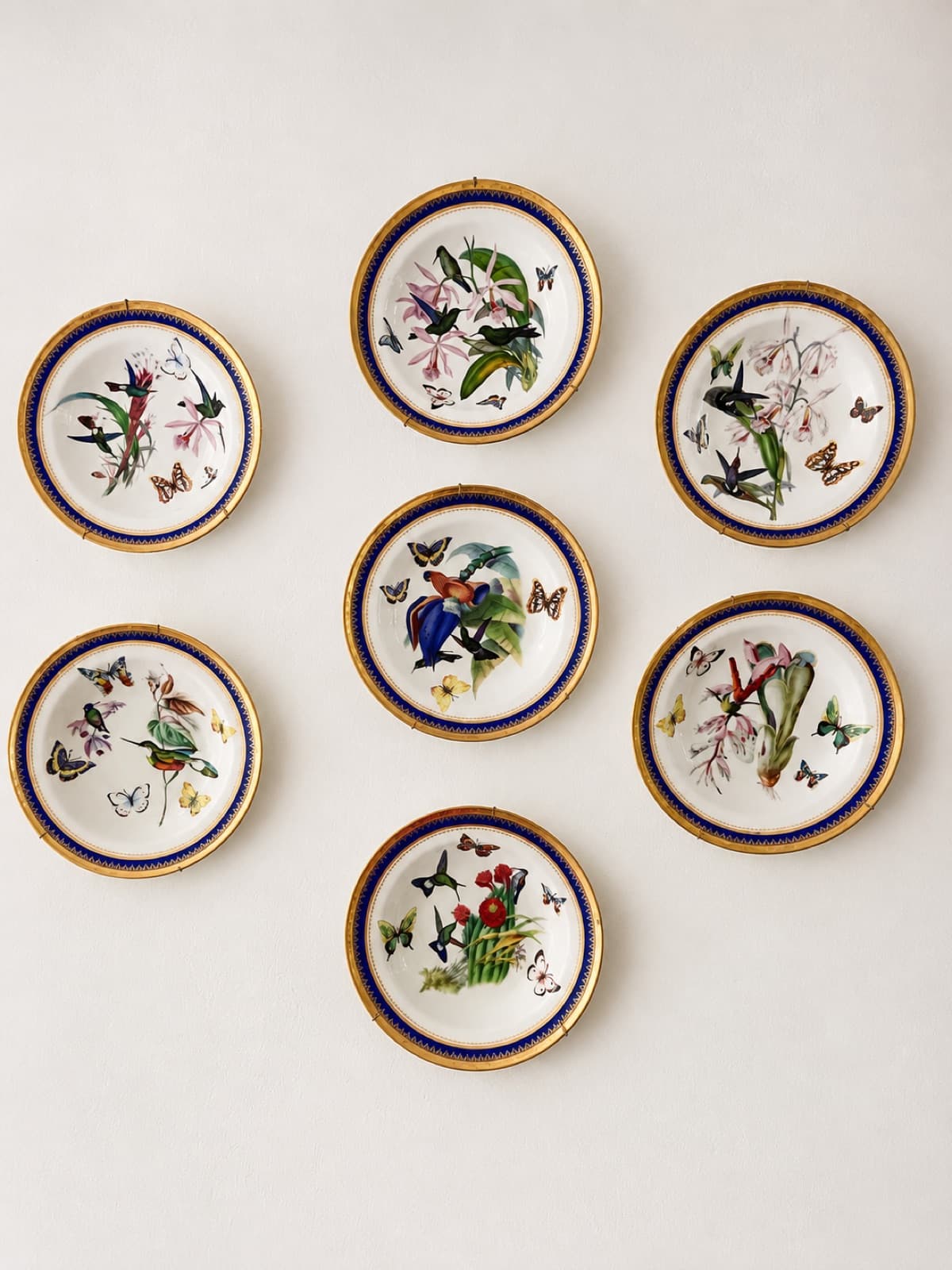 Pratos decorativos com pássaros e borboletas na parede da pousada