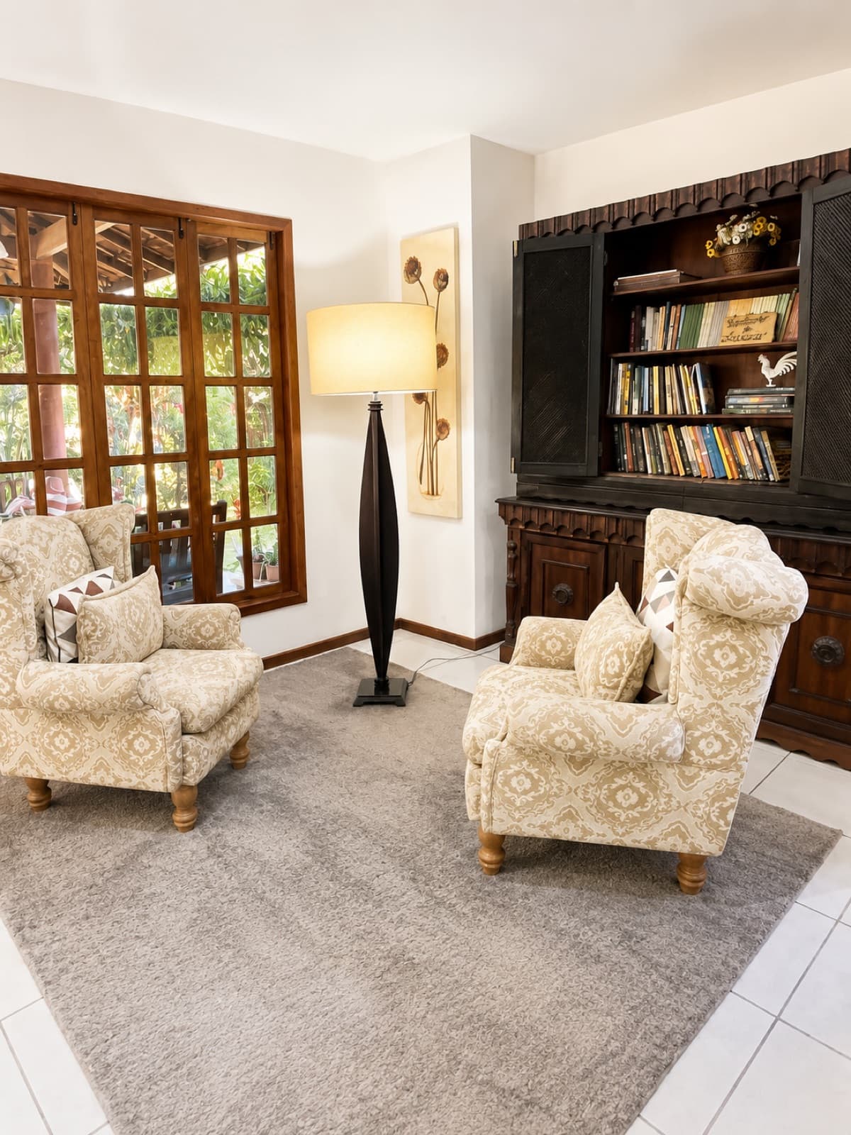 Sala de leitura com poltronas claras e estante de livros