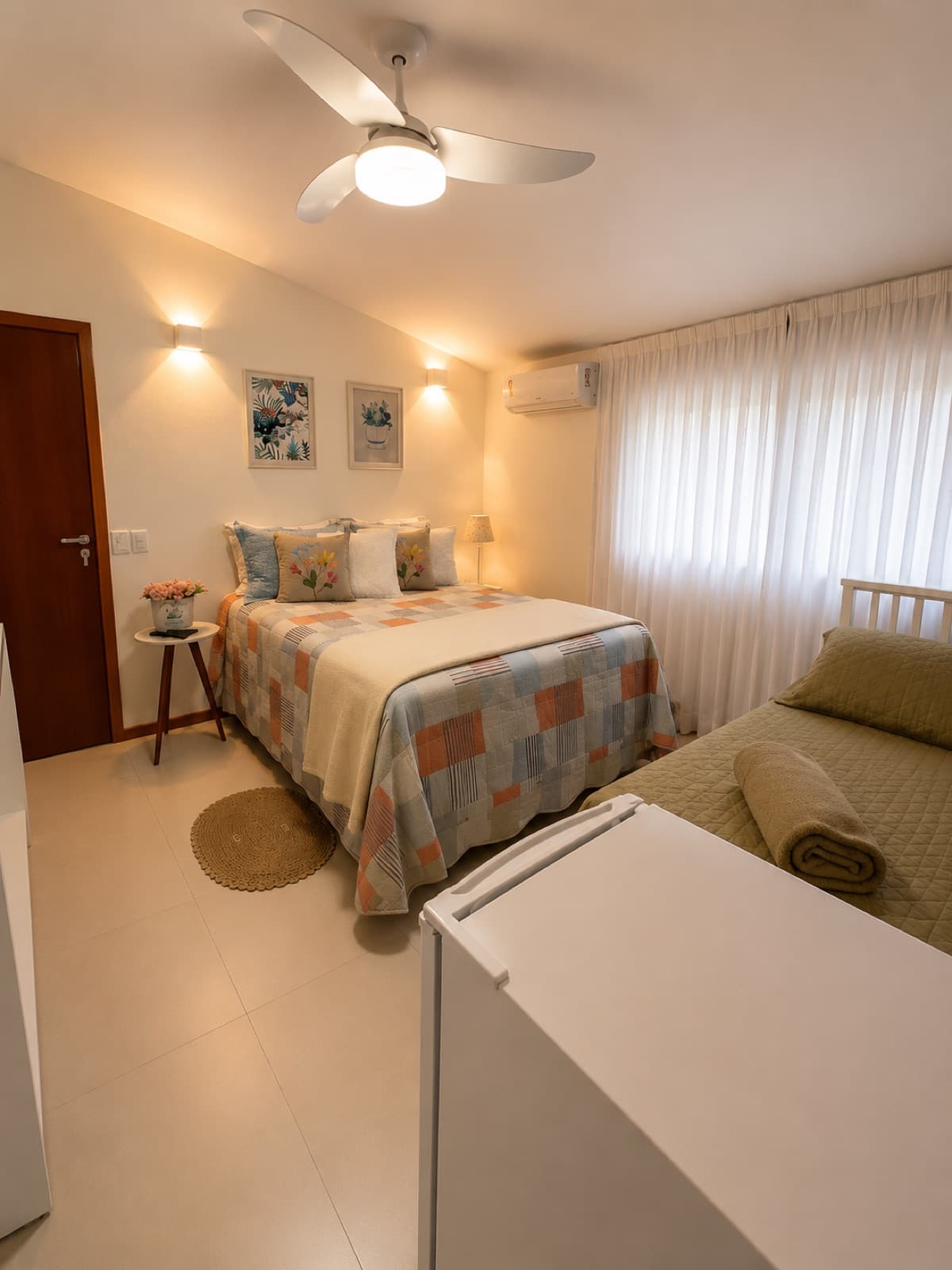 Quarto com cama de casal, cama de solteiro extra, frigobar e ventilador de teto