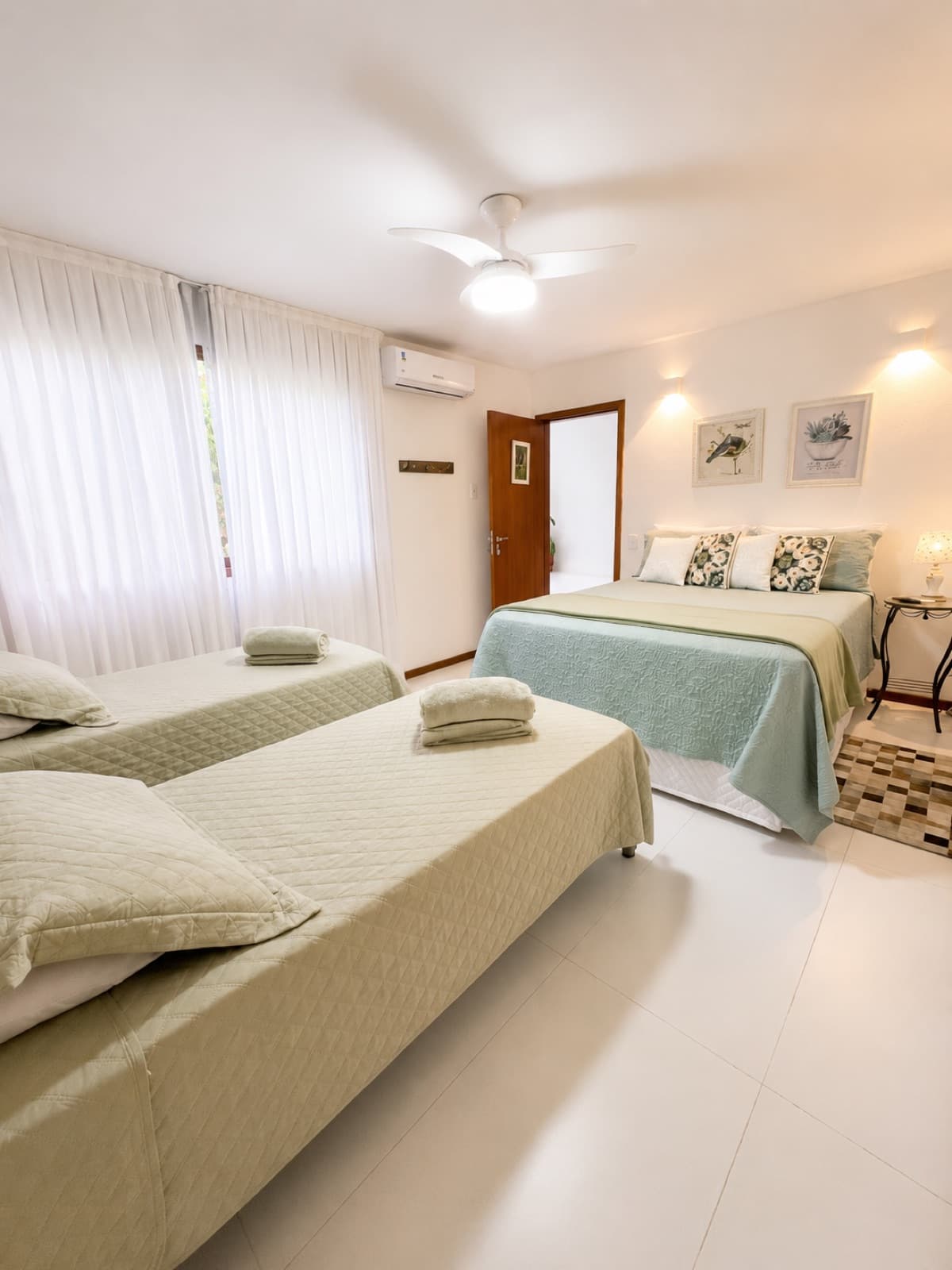 Quarto com cama de casal e cama de solteiro, com enxoval em tons de verde