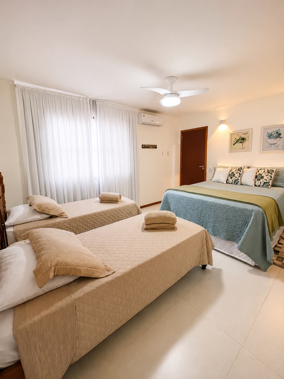 Quarto amplo com cama de casal e duas camas de solteiro, ideal para família