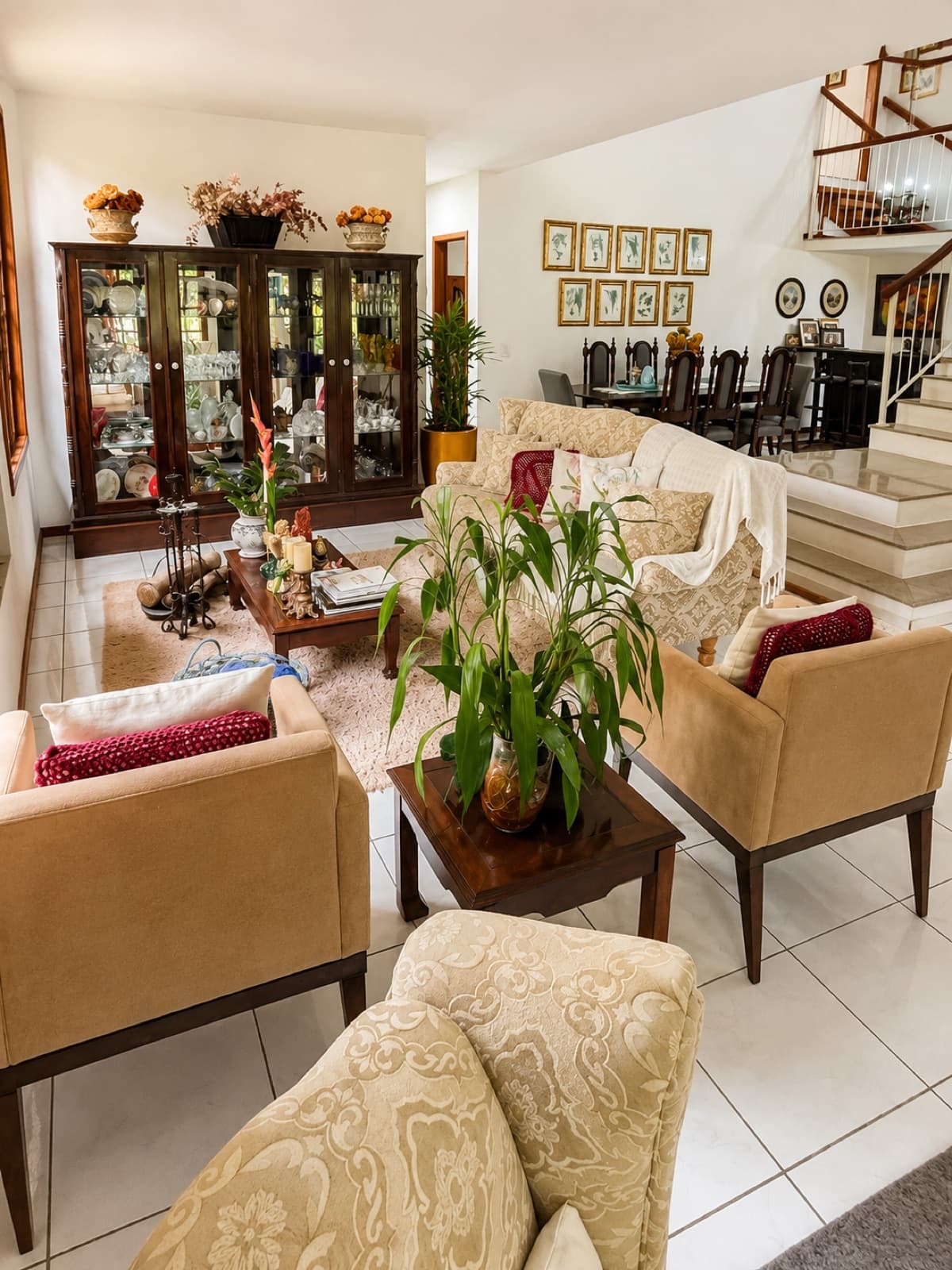 Sala de estar da Pousada Valle di Trento com poltronas, plantas e escada de madeira